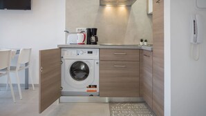 Une cuisine compacte équipée d’un lave-linge intégré, d’une machine à café et d’un téléphone.