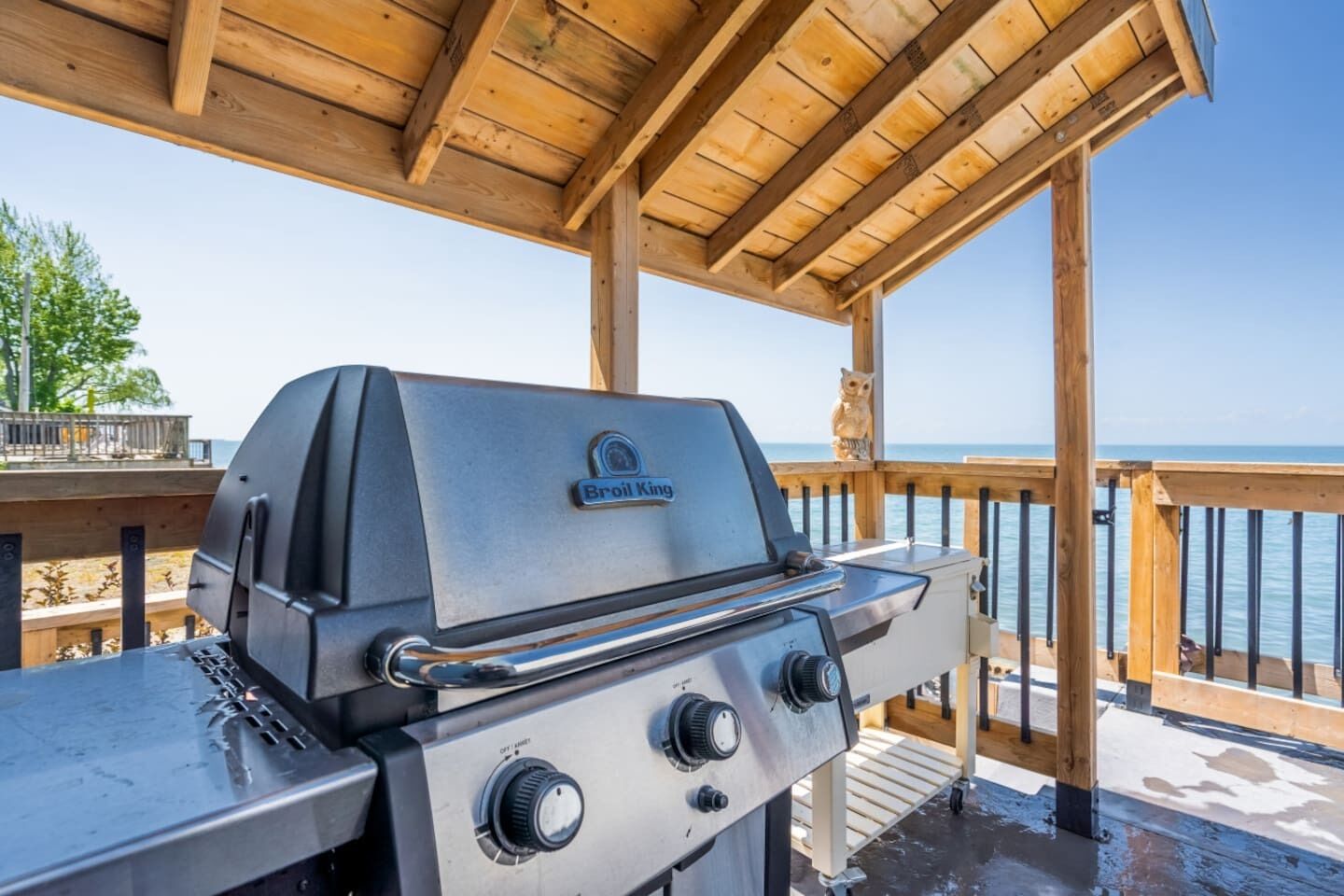 A Broil King grill on a wooden deck with a view of the ocean.