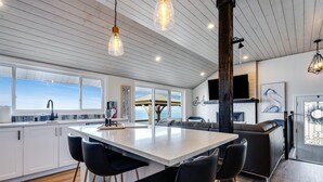 A modern kitchen with a large island, bar stools, and a view of the ocean. - Lake Erie Luxury Retreat  Hot Tub + Private Beach + Sunset Views (Leamington)