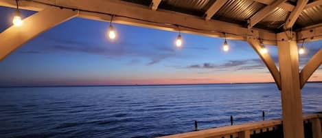 Une terrasse en bois offrant une vue sur l’océan au coucher du soleil.