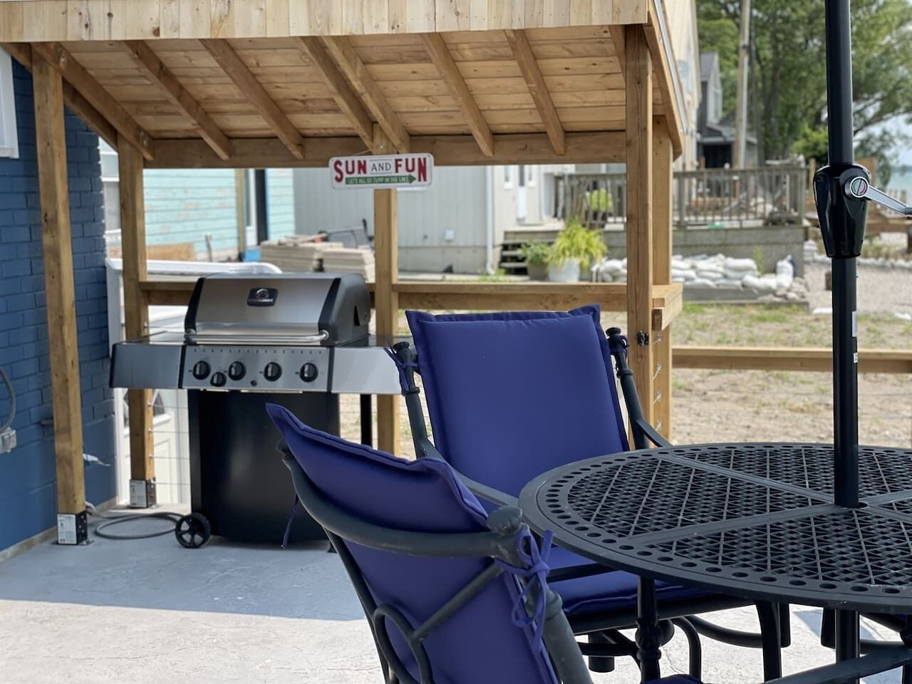 A patio area with a grill, two chairs, and a table.