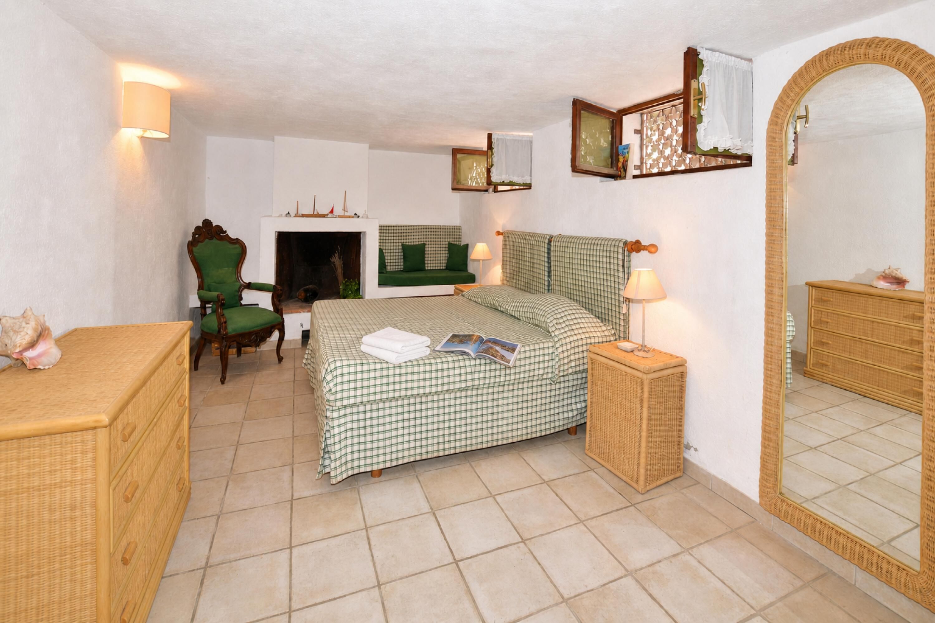 Une chambre à coucher avec un lit, une chaise, une commode, un miroir et une cheminée.