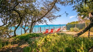 A coastal view with a beach, red chairs, and a cactus garden. - Casa Giannellina (Orbetello)