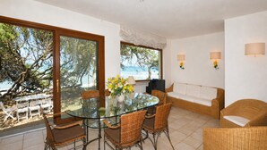 A dining area with a glass table, wicker chairs, and a view of the beach. - Casa Giannellina (Orbetello)