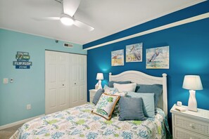 Un dormitorio con una cama, dos lámparas de pared, un ventilador de techo y tres cuadros.