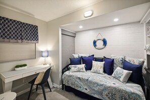 A bedroom with a bed, desk, and chair.