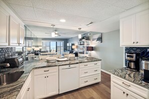 Una cocina moderna con encimeras de granito, armarios blancos y un comedor con vistas.