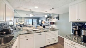 A modern kitchen with white cabinetry, granite countertops, and a central island. - XPLORIE ACTIVITIES & LINENS INCLUDED*! PLAZA - 2BR w/Enclosed Den. Amazing ocean views from the balcony! (Ocean City)