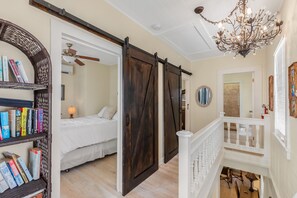 A bedroom with a bed, a bookshelf, and a sliding barn door. - SAILOR HOUSE ~ Charming 2 Bedroom, 1.5 Bathroom Just Steps to Duval St! (Key West)