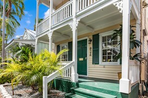 Charming two-story house with a traditional front porch and lush greenery.