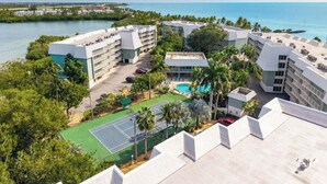 Un complejo turístico con varias construcciones, cancha de tenis y piscina.