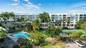 Un hotel con varios balcones, piscina y palmeras.