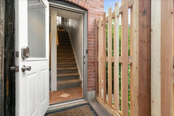 A wooden gate leading to a staircase inside a building with a brick exterior. - Beautiful Carriage House | Near Botanical Gardens | On site parking (denver)