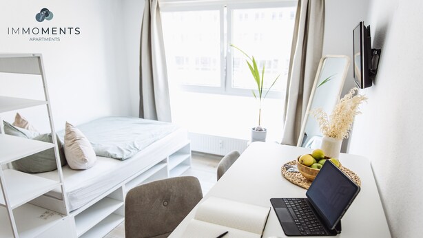 A modern bedroom with a bunk bed, a desk with a laptop, a notebook, and a cup of coffee.