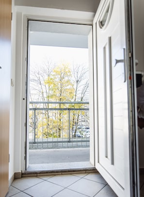 A view from a balcony with a metal railing, looking out onto a street with parked cars and trees with yellow leaves. - Apartment 2 minutes walk from the main station with Netflix (Magdeburg)