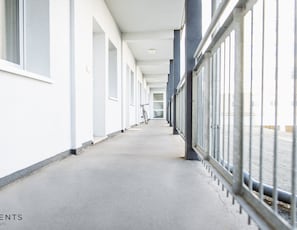 A corridor with a bicycle leaning against the wall, white walls, and a metal railing on the right. - Apartment 2 minutes walk from the main station with Netflix (Magdeburg)