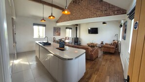 A spacious living area with a kitchen island, wooden flooring, a fireplace, and a television mounted on the wall. - Hot Tub*,Fire, Super-king , Zip n Link beds.Views (PRESTON)