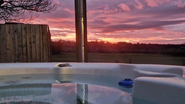 A hot tub with a wooden fence and a sunset in the background. - Hot Tub*,Fire, Super-king , Zip n Link beds.Views (PRESTON)