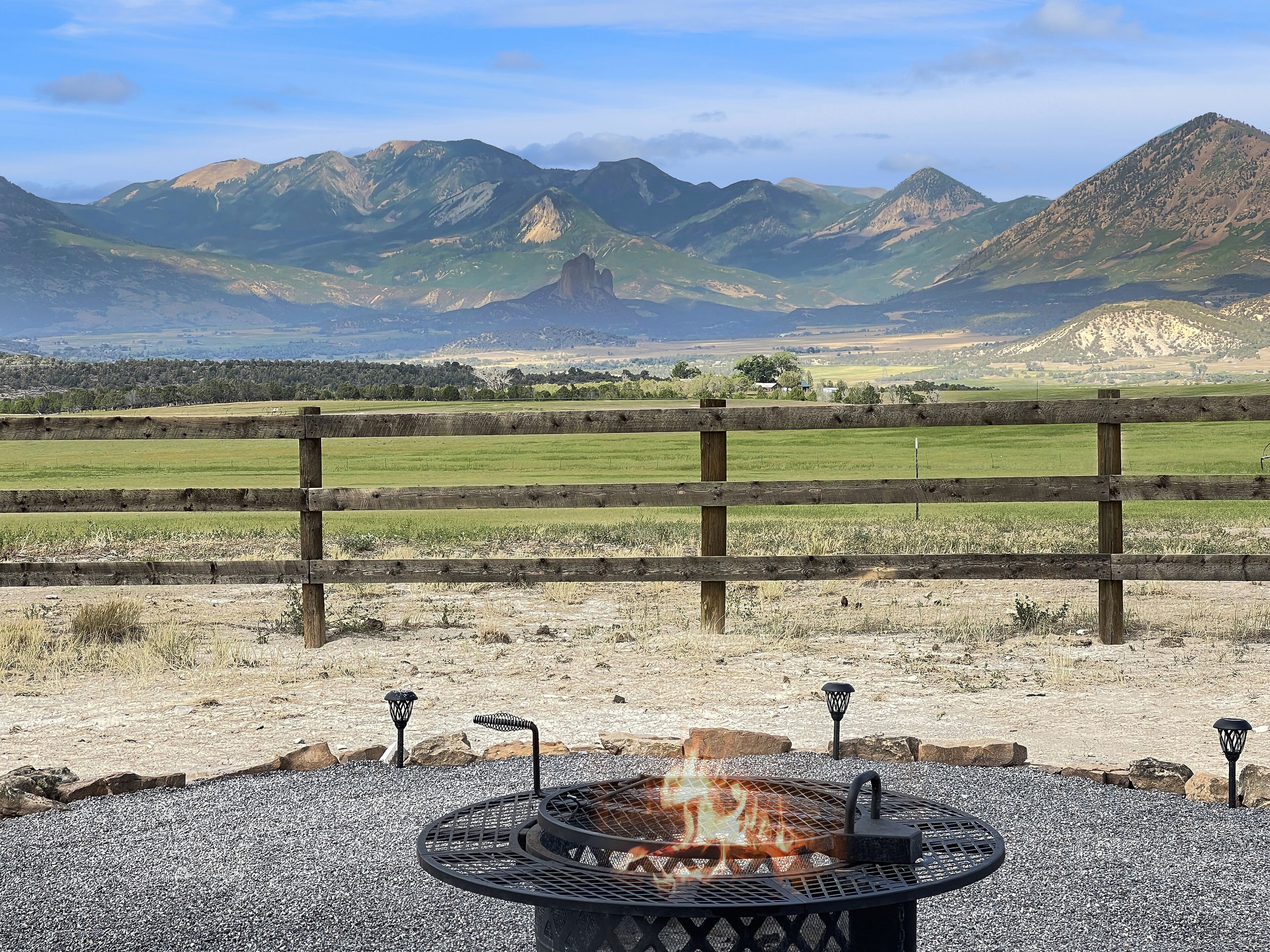 A fire pit with a view of mountains and a wooden fence.
