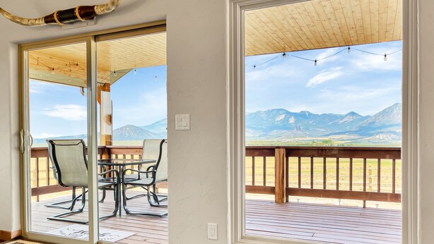 A room with a large sliding glass door leading to an outdoor deck with a view of mountains. -  Cabin with Jaw-dropping Views near Black Canyon (Crawford)