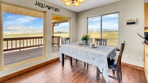 A dining area with a table set for two, large windows offering a view of the outdoors, and a 'Live Laugh Love' sign on the wall. -  Cabin with Jaw-dropping Views near Black Canyon (Crawford)