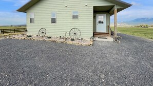 A light green building with a star on the roof, a porch, and a gravel driveway. -  Cabin with Jaw-dropping Views near Black Canyon (Crawford)