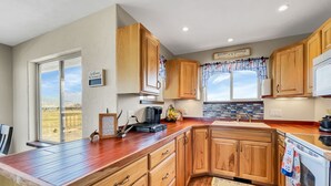 A kitchen with wooden cabinets, a large window, a coffee maker, and a view of the outdoors. -  Cabin with Jaw-dropping Views near Black Canyon (Crawford)