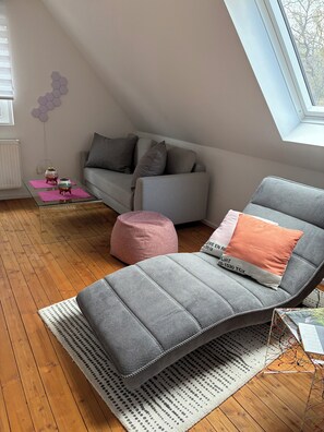 Una sala de estar moderna con un sofá, un sillón reclinable, una mesa de centro y una ventana.