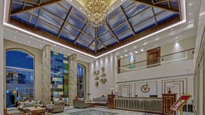 A spacious lobby with a high ceiling, a reception desk, comfortable seating, and a large window offering a view. - Grand Victoria The Fern Resort & Spa, Panchgani (Wai)