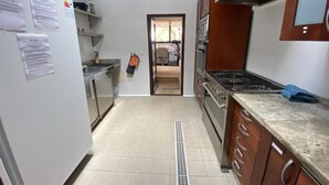 A kitchen with stainless steel appliances, wooden cabinets, and a tiled floor. - Beautiful Finca Sa Canova Agroturismo in Campos (Campos)