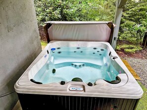 A hot tub with a control panel, surrounded by greenery. - Modern Lodge | Hot Tub | EV Charger | Near Blue Ridge Pkwy (Boone)