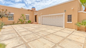 Una casa de fachada color beige, una puerta de garaje blanca y una estructura pequeña en forma de cúpula en el techo.
