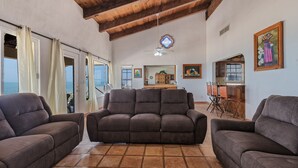 Un amplio espacio de sala con un sofá grande, una mesa de comedor y una cocina al fondo.