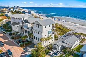 A multi-story hotel with a beach view, featuring a parking area and a pool.