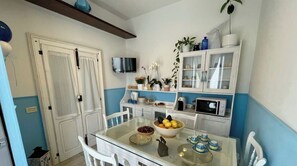 Enjoy meals at the glass-top dining table for four, with a microwave and refrigerator nearby.