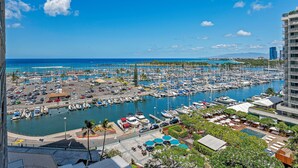 Un puerto deportivo con numerosas embarcaciones amarradas, un cielo azul despejado y vista al océano.
