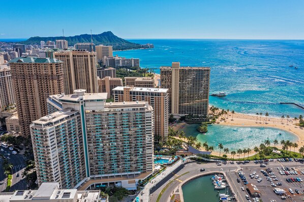 A high-rise hotel with multiple floors, a beach, and a clear view of the ocean.