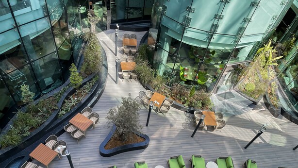 Et moderne atrium med buede stier, siddeområder og indeplanter.