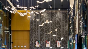 En moderne lobby med receptionsdisk, siddeområde og dekorativ belysning.