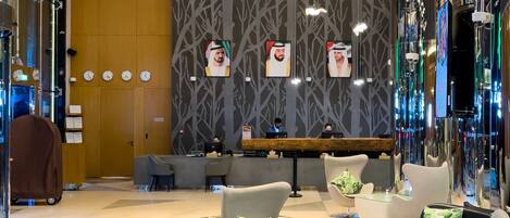 A modern lobby with a reception desk, seating area, and decorative lighting.