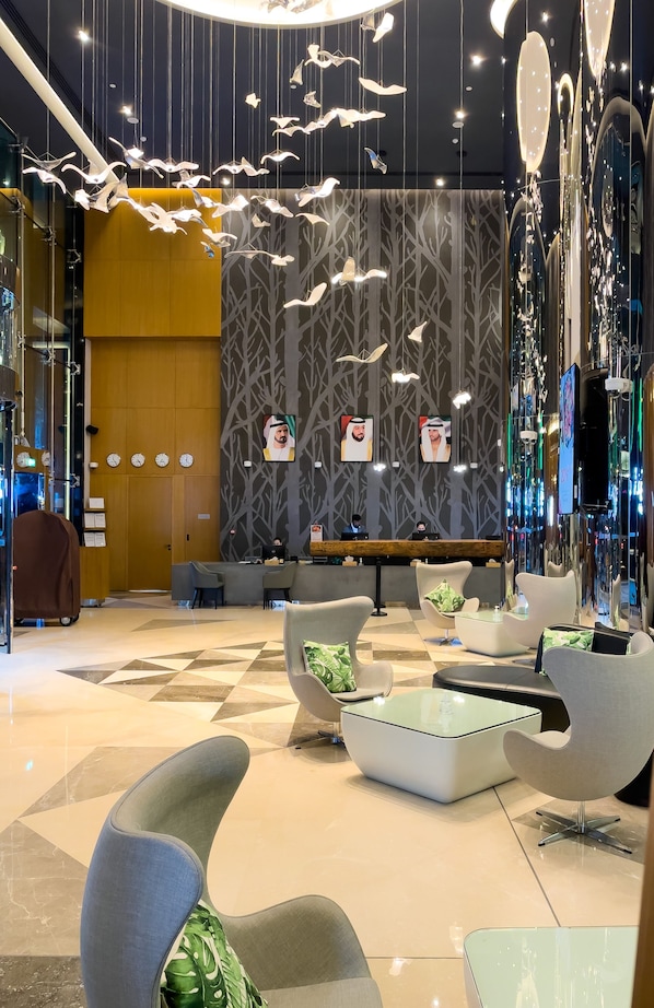 Un vestíbulo moderno con mostrador de recepción, zona de estar e iluminación decorativa.