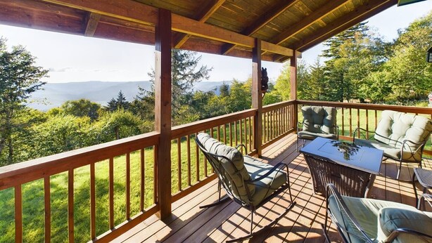 Una terraza de madera con muebles exteriores y vistas a montañas.