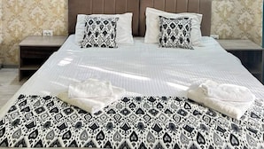 A hotel room with a large bed, two nightstands, a modern headboard, patterned wallpaper, and a large abstract painting on the wall. - Artist Regency Hotel (Tashkent)