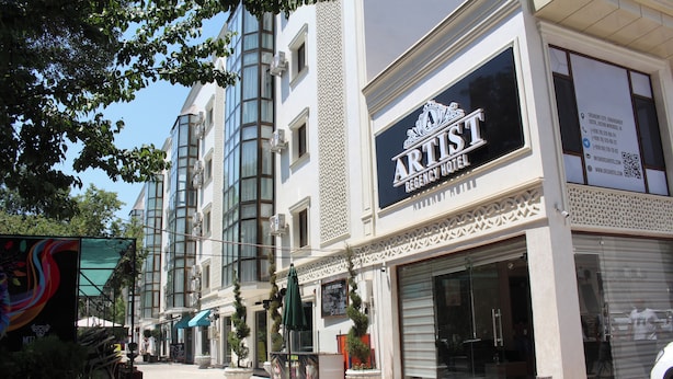 A Regency Hotel with a modern facade, large windows, and a brick-paved street. - Artist Regency Hotel (Tashkent)