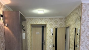 A hotel room with a wooden floor, a bed, a desk, and a chair. There are two doors, one with a 'No Entry' sign, and a mirror on the wall. - Artist Regency Hotel (Tashkent)