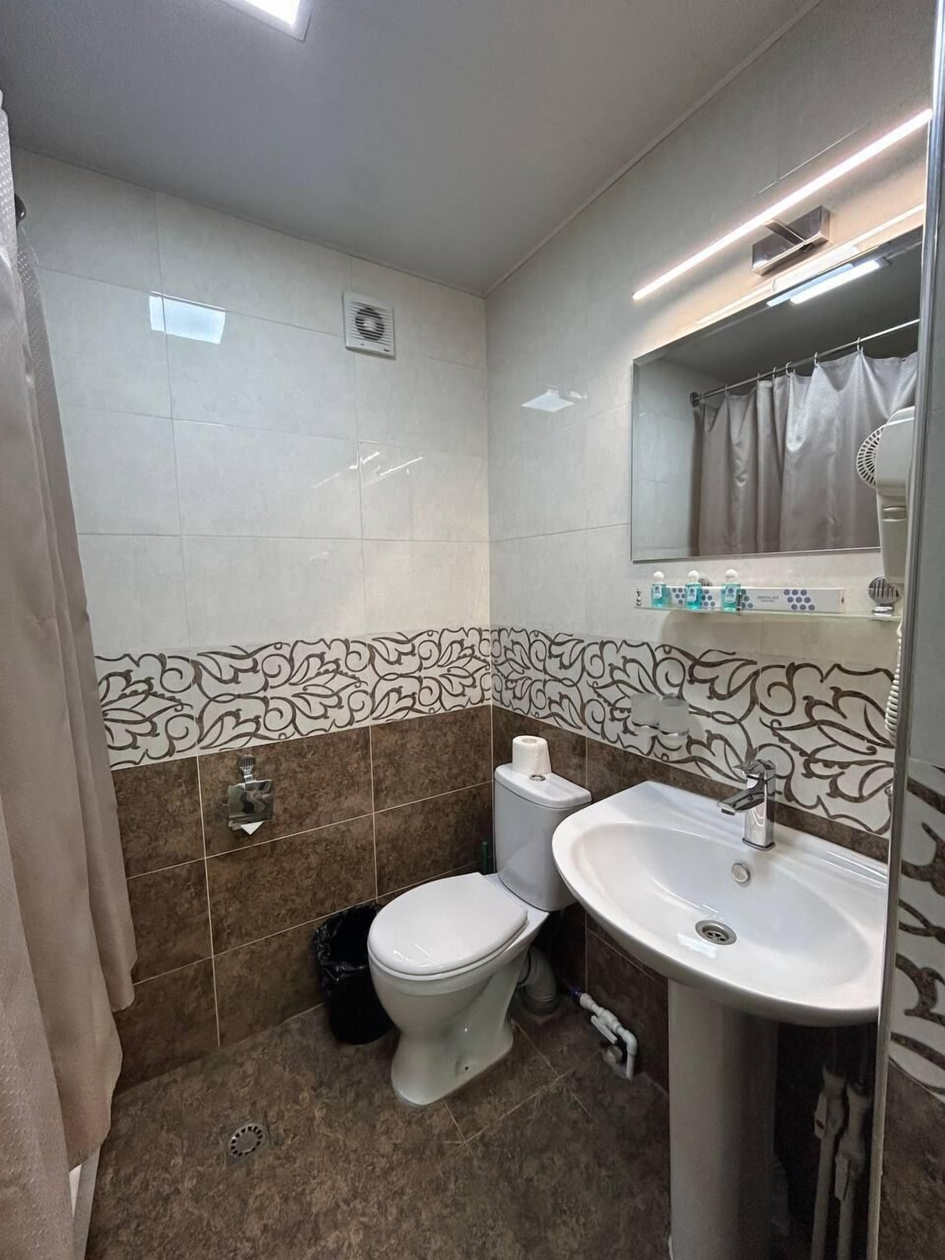 A bathroom with a toilet, sink, and shower area.