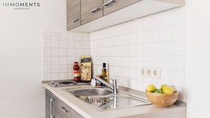 Une cuisine moderne avec des carreaux blancs, des appareils électroménagers en acier inoxydable et des meubles de cuisine en bois.