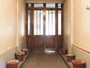 A hallway with a wooden double door, flanked by six terracotta pots on the floor. - Nice Studio Near Eiffel Tower (Paris)