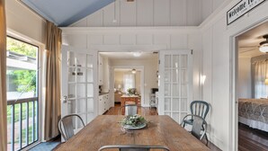 A dining area with a wooden table, metal chairs, and a welcome sign. - Reizend Haus 2 Bedroom Home by RedAwning (Fredericksburg)