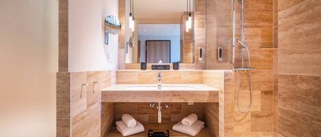 A modern bathroom with a large mirror, a sink, a shower, and a towel rack.